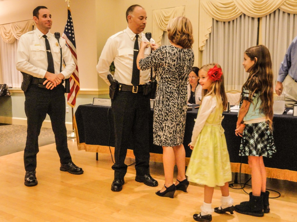 Frank Lee receives his captain's badge from his wife, Sarah, as their daughters look on. Credit: Matt Skoufalos.