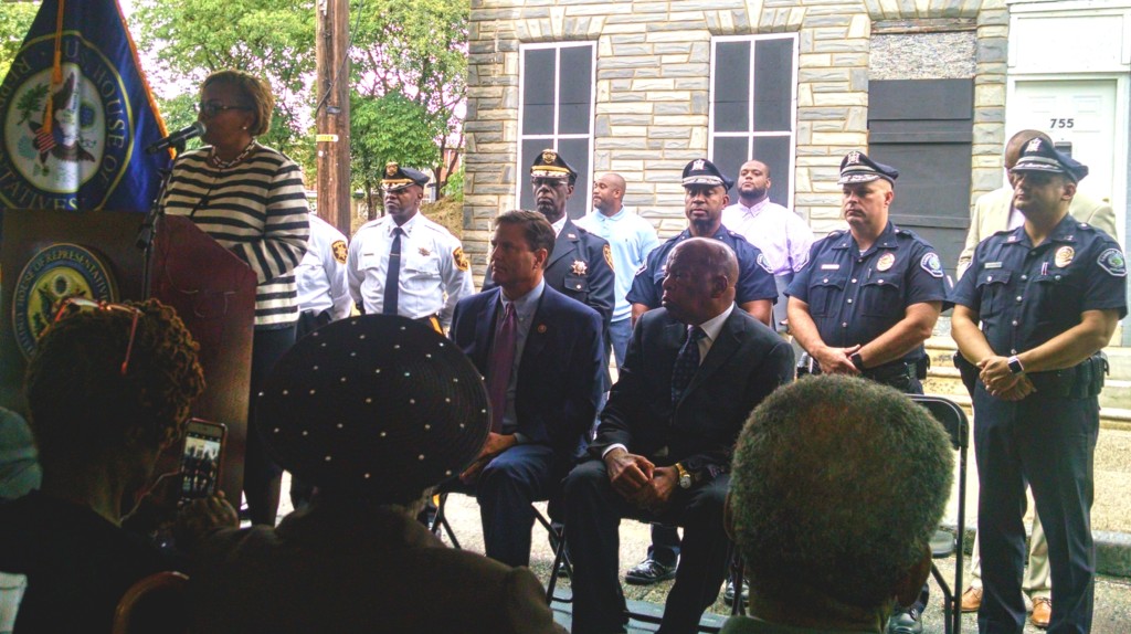 Camden City Mayor Dana Redd addresses a crowd on Chestnut Street; seated are Reps. Norcross and Lewis. Credit: Matt Skoufalos.